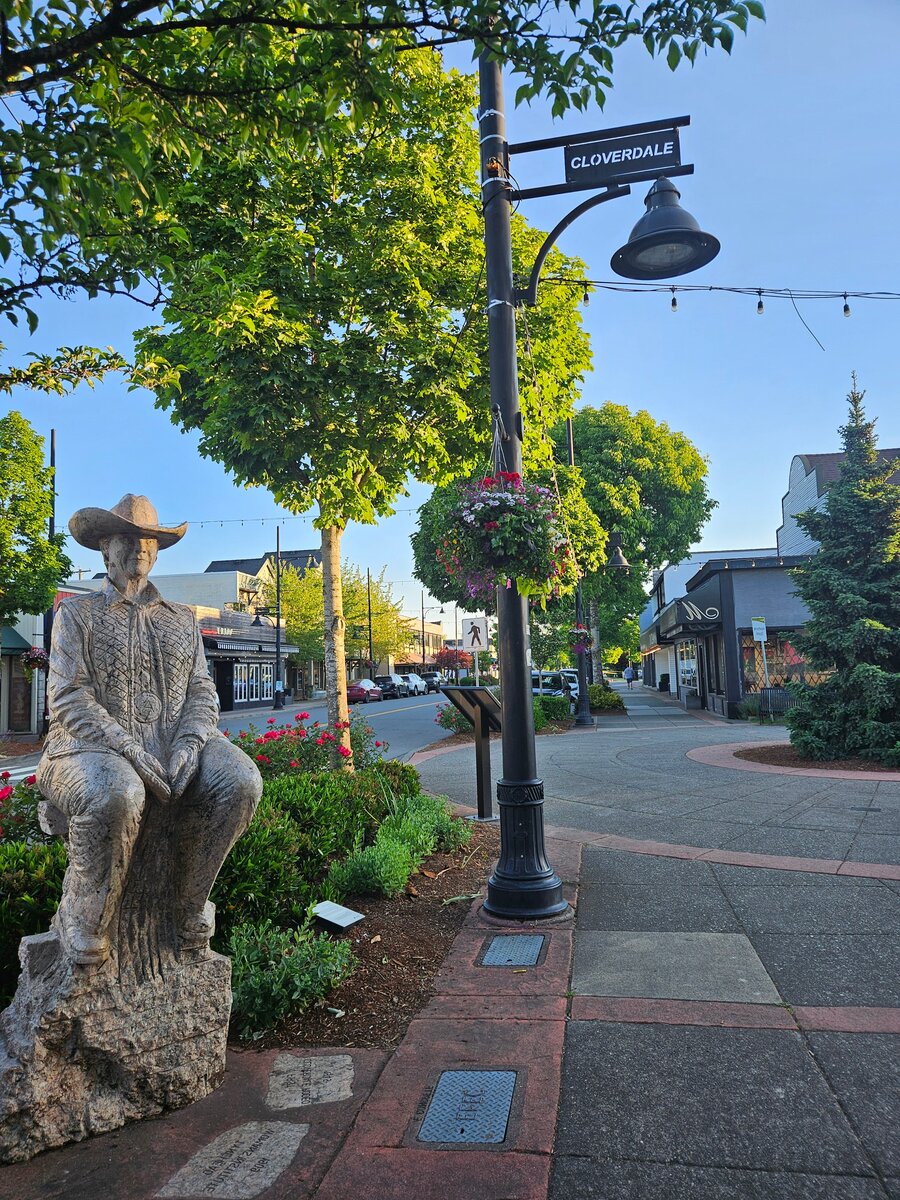 Downtown Cloverdale street scene with historic lamp post, cowboy statue, and hanging flower baskets